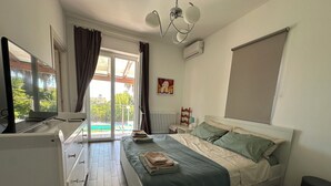Une chambre à coucher comprenant un lit, un bureau, une chaise, une fenêtre avec des rideaux, un radiateur et un ventilateur de plafond.