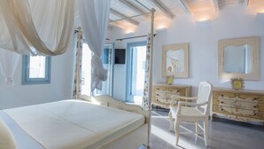 Ein Schlafzimmer mit Baldachinbett, einem Schminktisch, einem Sessel und einem Fernseher.