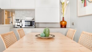 A modern kitchen with white cabinets, a microwave, a coffee machine, and a dining table with wicker chairs. - Exclusive house in Sitges center with pool and terraces, steps from beach (Sitges)