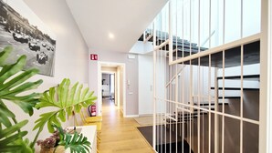 A modern hotel interior with a wooden floor, a staircase with a glass railing, and a fire extinguisher on the wall. - Exclusive house in Sitges center with pool and terraces, steps from beach (Sitges)