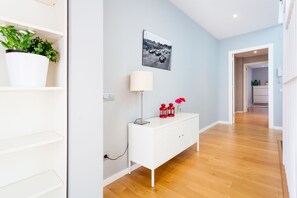 Experience the sleek, modern design of this stylish hallway, featuring a console table, artwork, and lush greenery.