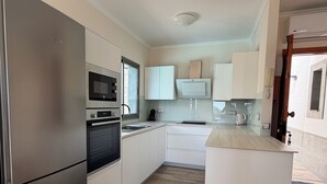 A modern kitchen with white cabinetry, a built-in oven, a microwave, and a sink. - House / Villa - Tauro - Mogán (Mogan)