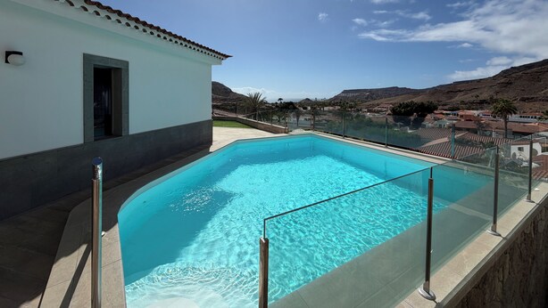 A swimming pool with a clear view of the surrounding landscape and a building with a tiled roof. - House / Villa - Tauro - Mogán (Mogan)