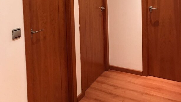 Una habitación con dos puertas de madera, un equipo de aire acondicionado arriba y suelo de madera.