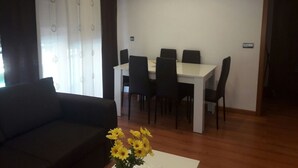 Una sala de estar con un sofá, una mesa de comedor con sillas y un florero.