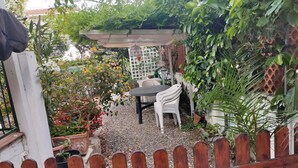 A garden patio with a table and chairs, surrounded by potted plants and a wooden fence. - Apartment with garden in Castiglioncello (Rosignano Marittimo)