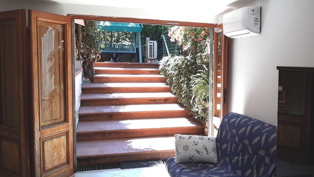 A staircase leading to a covered outdoor area with a bench and a potted plant. - Apartment with garden in Castiglioncello (Rosignano Marittimo)