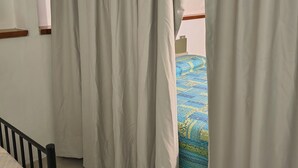 A room with a bed, a window with curtains, a radiator, and a wall-mounted air conditioning unit. - Apartment with garden in Castiglioncello (Rosignano Marittimo)
