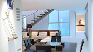 A modern interior with a dining area, a staircase, and a Buddha statue.