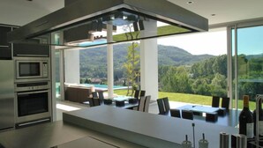 A modern kitchen with a large island, built-in appliances, and a view of a pool and mountains.
