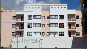 Un edificio residencial de varios pisos con balcones, techo plano y cielo despejado.