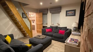 A modern living room with a staircase, a sofa set, and a coffee table. - Fossil Bank, a luxury detached retreat in the heart of Alnmouth, with parking (Alnmouth)