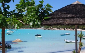 A beach with clear turquoise water, several boats, and a thatched-roof structure. - Mini Villa with sea view terrace, 5 minutes on Spia's all inclusive rates (Porto-Vecchio)
