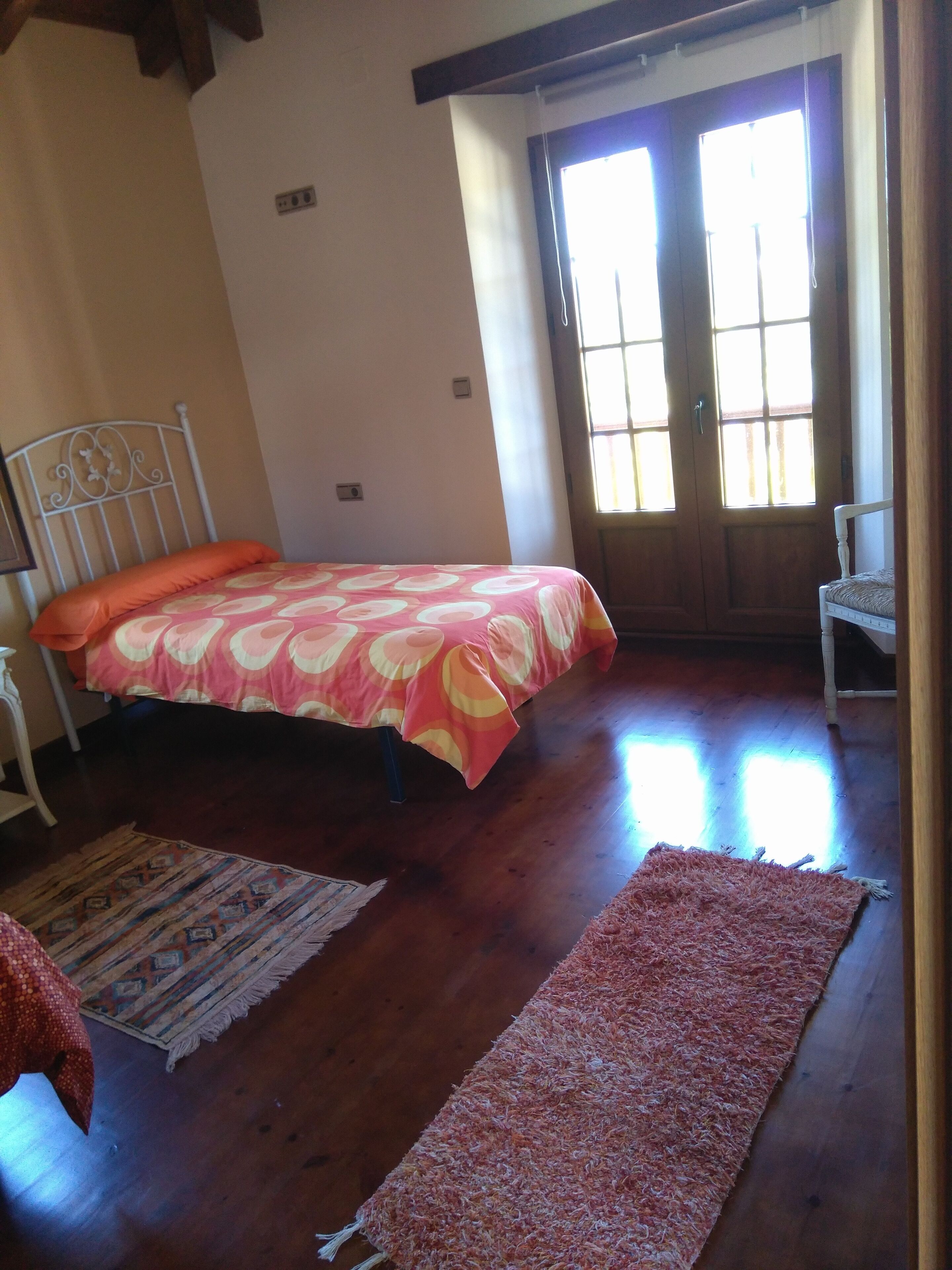 A bedroom with a bed, a chair, a rug, and a window.