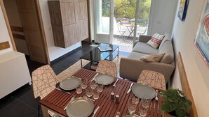 A modern living room with a dining area, a sofa, a TV, and a view to the outside. - Apartment Llanca Sea view, Swimming pool and 5min walk to the beach (Llanca)