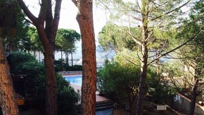 A private property with a stone pathway leading to a swimming pool surrounded by trees and greenery. - Apartment Llanca Sea view, Swimming pool and 5min walk to the beach (Llanca)