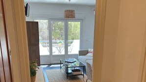 A modern interior with a glass table, a sofa, and a view of the outdoors through a sliding door. - Apartment Llanca Sea view, Swimming pool and 5min walk to the beach (Llanca)