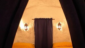 A cozy room with two beds, a dark curtain, and two wall-mounted lanterns providing light. - Troglodyte House Cueva Almendro, Granada Province (Free WiFi) (Guadix)