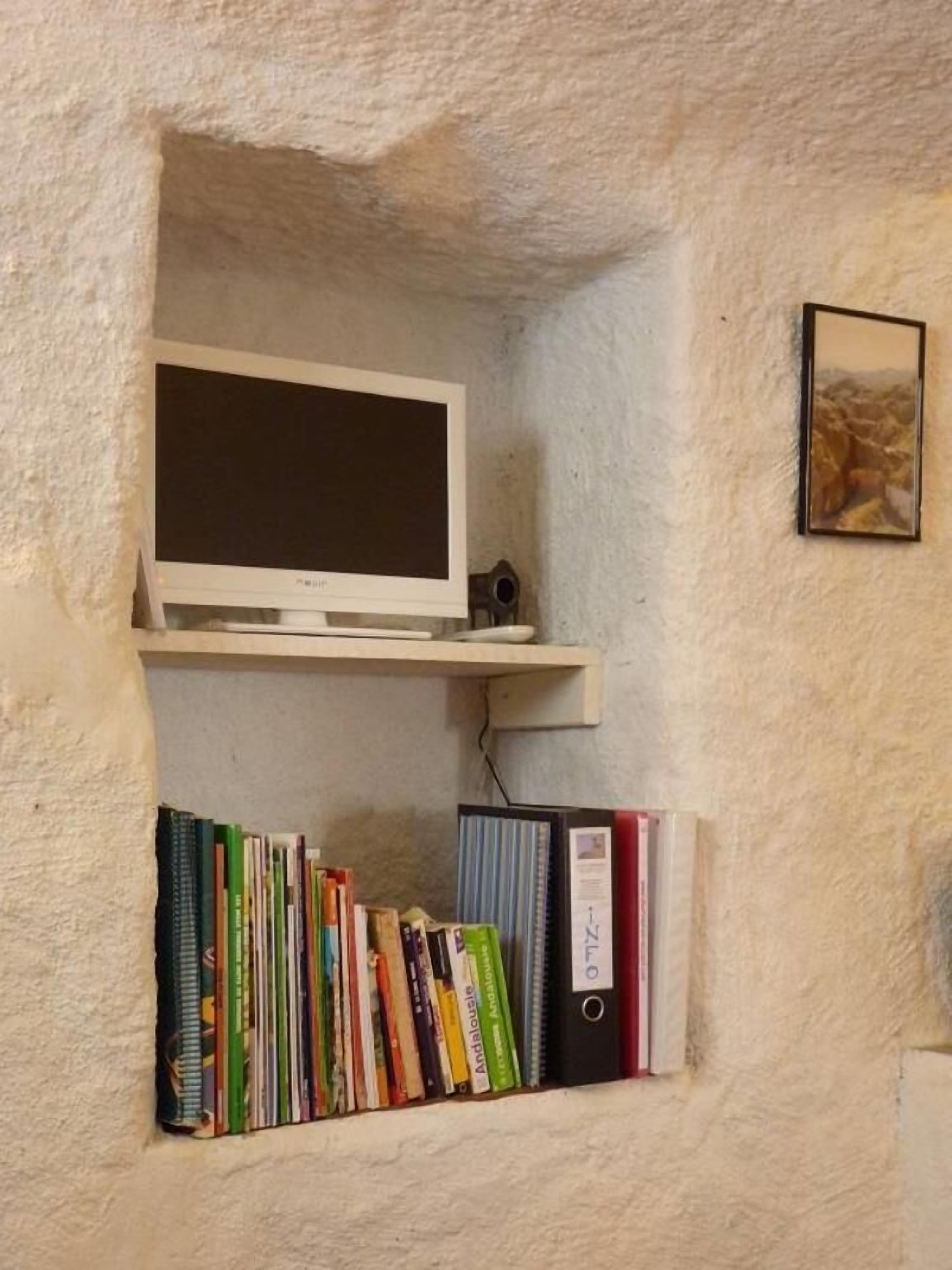 A bookshelf with books and a white monitor.