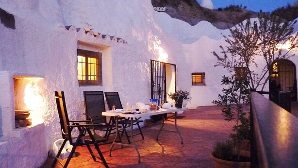 A cozy outdoor dining area with a table and chairs, surrounded by white walls and a tiled floor. - Troglodyte House Cueva Almendro, Granada Province (Free WiFi) (Guadix)
