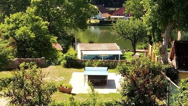 Una propiedad junto al lago con una casa pequeña, un patio y abundante vegetación.