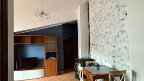 Un'ampia zona giorno con tavolo da pranzo, sedie, TV e angolo cottura.