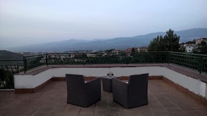 Una terrazza sul tetto con mobili in vimini e vista su montagne lontane.
