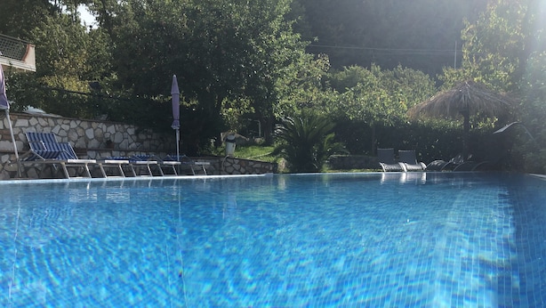 Una piscina cristallina blu con lettini e un muro in pietra.