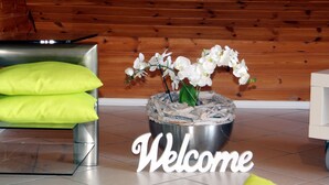 A modern interior with a metal bowl containing white orchids, a 'Welcome' sign, and a bright green sofa. - Modern and spacious attic apartment in Abtsteinach im Odenwald (Abtsteinach)
