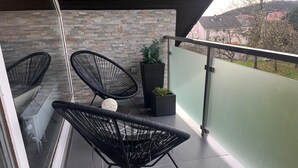 A balcony with two black wicker chairs, a small white spherical object, and two potted plants. - Modern and spacious attic apartment in Abtsteinach im Odenwald (Abtsteinach)