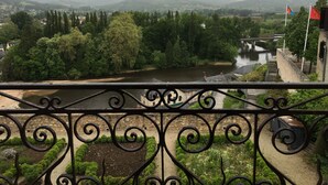 A riverside view from a balcony with a metal railing, a stone wall, and a bridge in the distance. - The Périgord houses on the abbey side  (Terrasson-Lavilledieu)