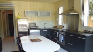 A modern kitchen with a central island, built-in appliances, and a window providing natural light. - GROUND FLOOR ALL COMFORT NEAR THE SEASIDE IN MOLINI-AGOSTA (Albitreccia)