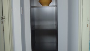 A narrow hallway with a black shelving unit containing a yellow pot on the top shelf. - GROUND FLOOR ALL COMFORT NEAR THE SEASIDE IN MOLINI-AGOSTA (Albitreccia)