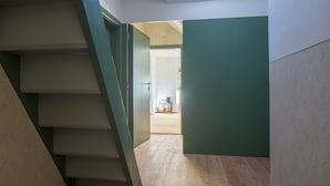 Uma escadaria que leva a um quarto com piso de madeira e paredes verdes.