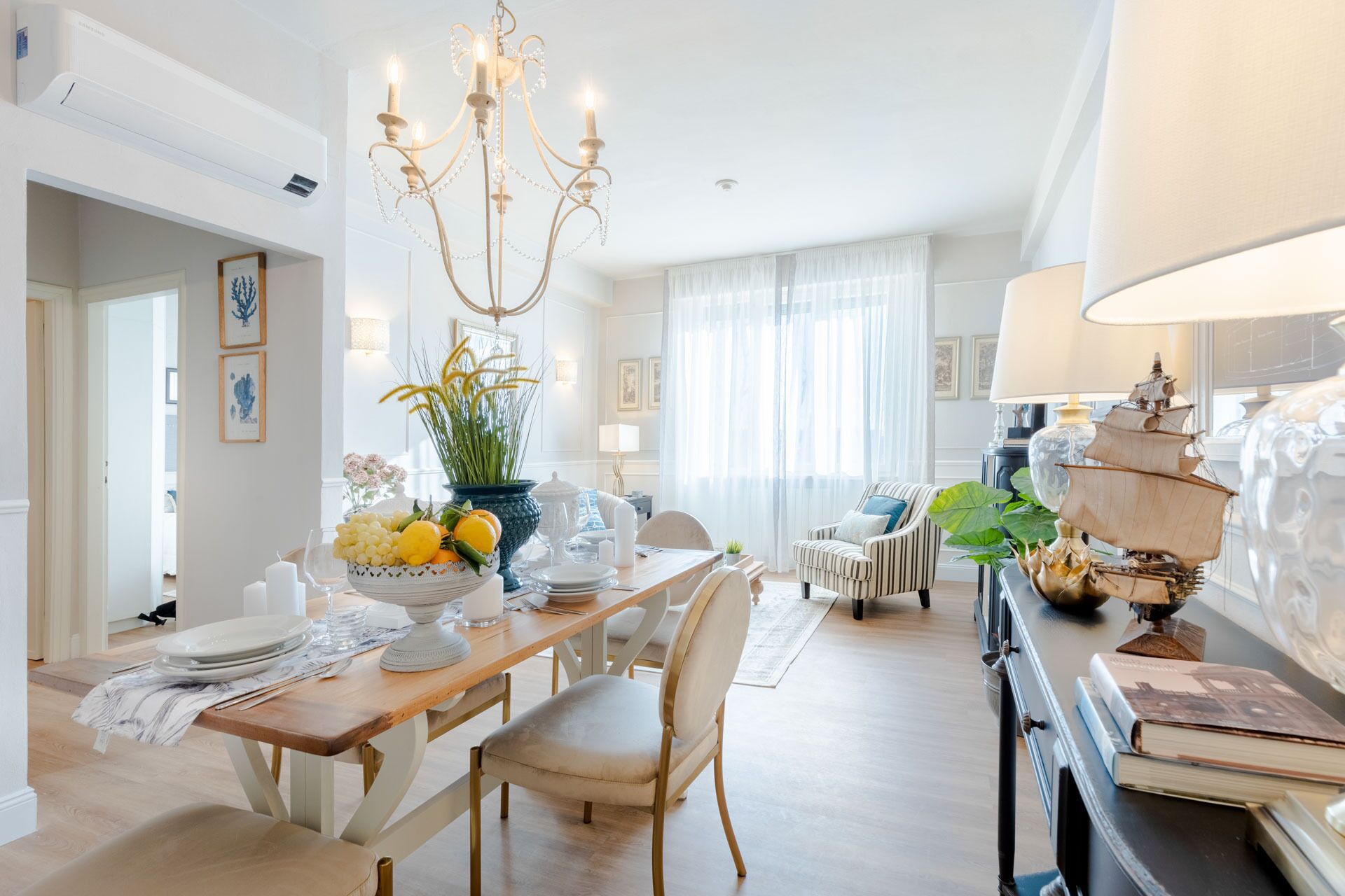 Un'area pranzo con un lampadario, un tavolo apparecchiato per quattro e una lampada a forma di nave su un credenza.