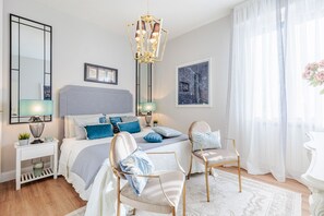 A bedroom with a large bed, two bedside tables, a chandelier, and a large window with sheer curtains. - Luxury location in front of the sea with private garage (Camaiore)