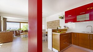 Een moderne keuken met rode kastjes, een houten keukeneiland en een zithoek met een bank en tafel.