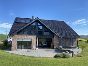 Une maison moderne dotée d’une grande baie vitrée, d’une façade en briques et d’un toit en pente.