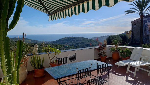 A terrace with a table and chairs, potted plants, and a view of the sea. - Picturesque apartment in a medieval village perched at top a mountain ridge (Imperia)