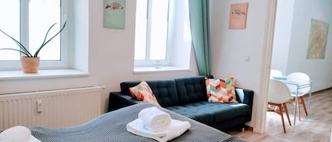 A modern hotel room with a bed, a sofa, and a dining area.