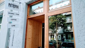 Een winkelgevel met een bord waarop staat 'AMBAVI' café, 'BIOLOGISCH ETEN', 'KOFFIE' en 'WIJN'.
