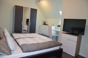 A bedroom with a bed, a wardrobe, a television, and a kitchenette. - Holiday apartment in modern country house style. 10 min bike path to the beach (Krokau)