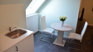 A compact kitchen with a sink, a dining table with chairs, and a skylight.