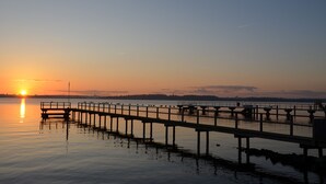 A pier extending into calm water with a sunset in the background.