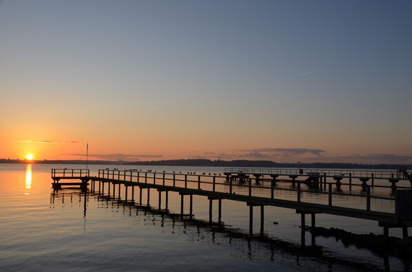 A pier extending into calm water with a sunset in the background. - Holiday apartment in modern country house style. 10 min bike path to the beach (Krokau)