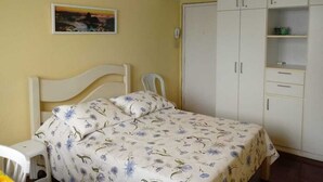Quarto com cama, guarda-roupa branco e um quadro na parede.