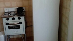 Uma cozinha compacta com geladeira branca, fogão com panela e pia pequena.