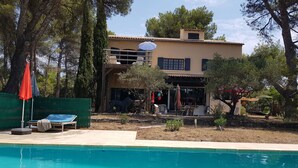 Área da piscina com espreguiçadeiras, uma estátua e mobiliário ao ar livre.