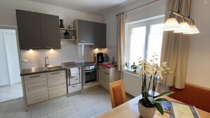 A modern kitchen with grey cabinets, a stainless steel sink, and a dining area with a table and chairs.