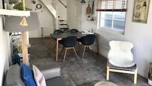 Una sala moderna con comedor, sofá gris, mesa de centro redonda y un sillón blanco mullido.